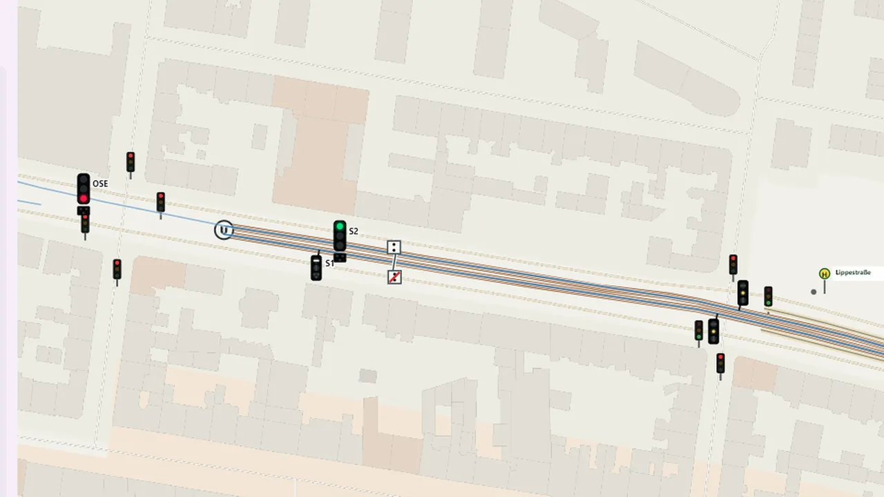 Straßenbahnstrecke an einer Kreuzung mit Autoampeln, Straßenbahnsignalen und Haltestelle.